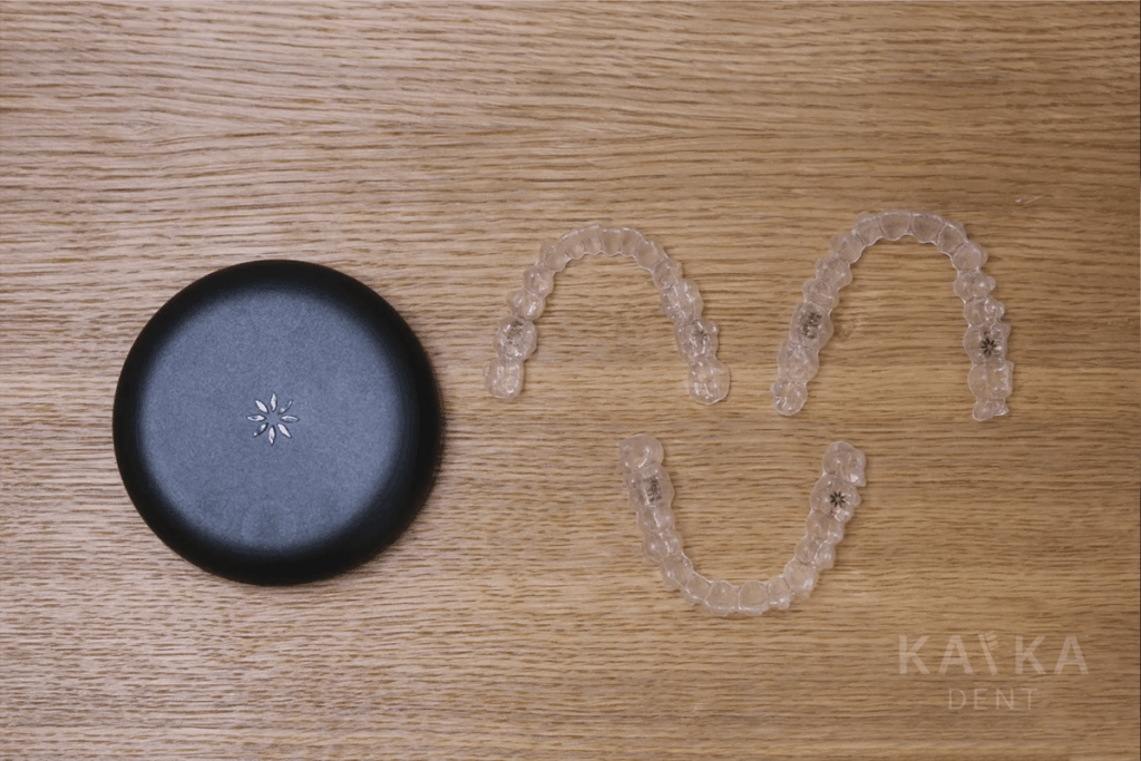 Dvojica priehľadných neviditeľných strojčekov Invisalign položených na stole